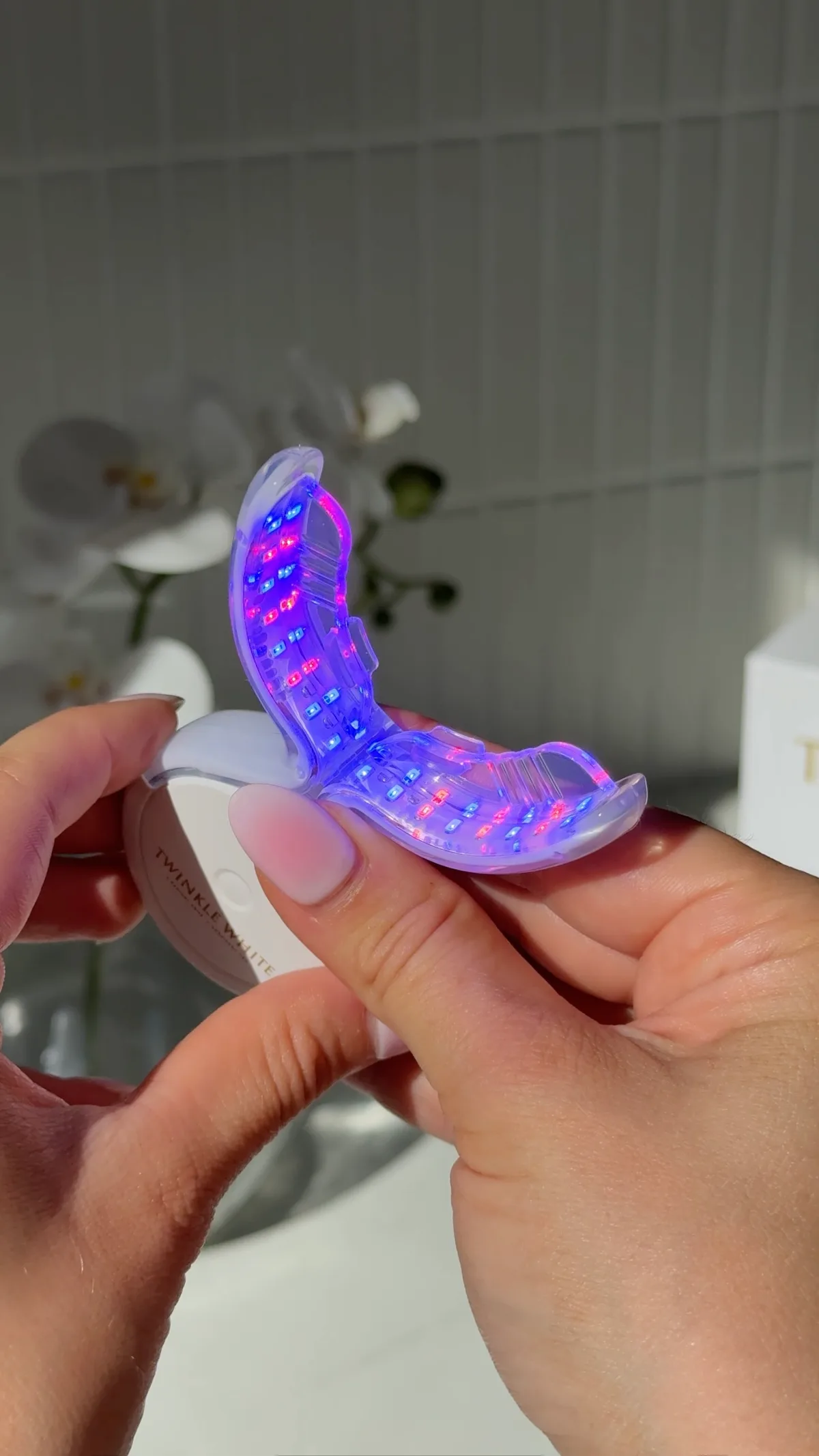 Twinkle White LED mouthpiece glowing blue and red during a whitening session